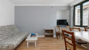 Un'area living con un divano, un tavolino, una TV e un tavolo da pranzo con sedie.