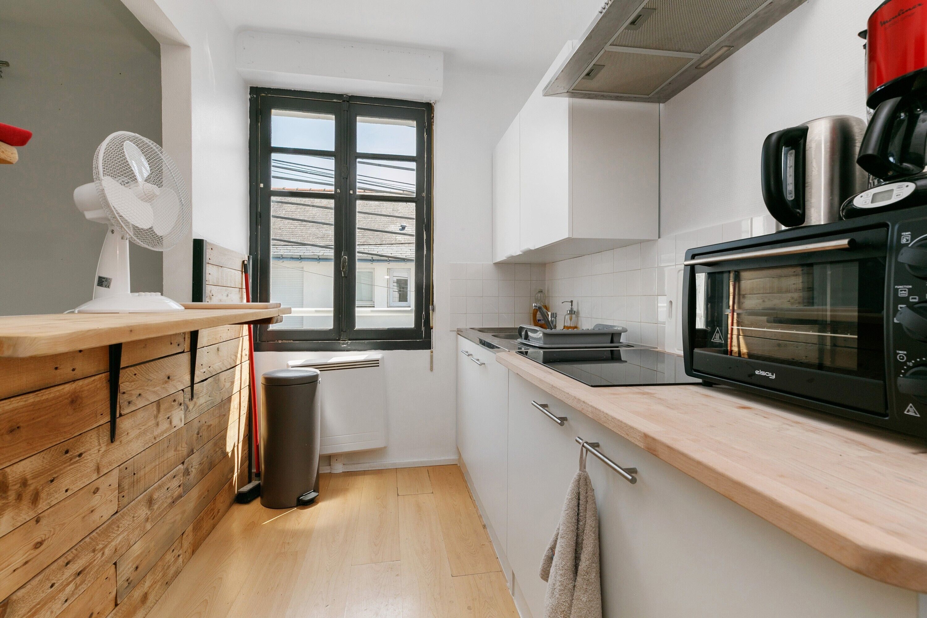 Cocina compacta con microondas, estufa y ventana que ofrece vistas al exterior.