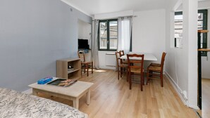 Un ambiente compatto con un letto, un tavolo da pranzo con sedie, una TV e una finestra con tende.