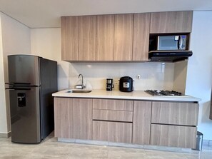 A compact kitchen with a built-in microwave, a coffee maker, and a stove. - Prime Location Sabaneta Studio + Great View (SABANETA)