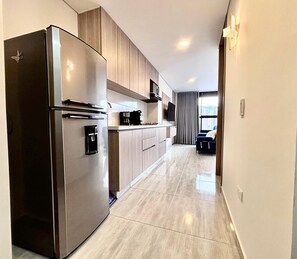 Eine moderne Küche mit einem Edelstahlkühlschrank, Holzschränken und einem Flachbildfernseher.