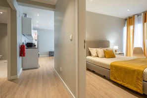 Et moderne hotelværelse med en seng, et natbord og udsigt til gangen.