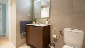 A modern bathroom with a wooden vanity, a large mirror, a toilet, and a towel hanging on a rack. - Cantinho da Fonte Apartment with Mountain View, Wi-Fi, and Air Conditioning (Agua de Pau)