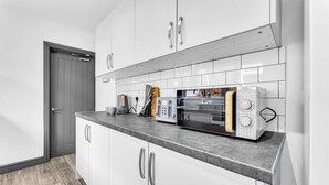 Een moderne keuken met witte kasten, een grijs aanrecht en een magnetron.