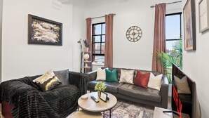 A modern living room with a sofa, coffee table, and a wall clock. - The Hallmark Birmingham Flat (Birmingham)