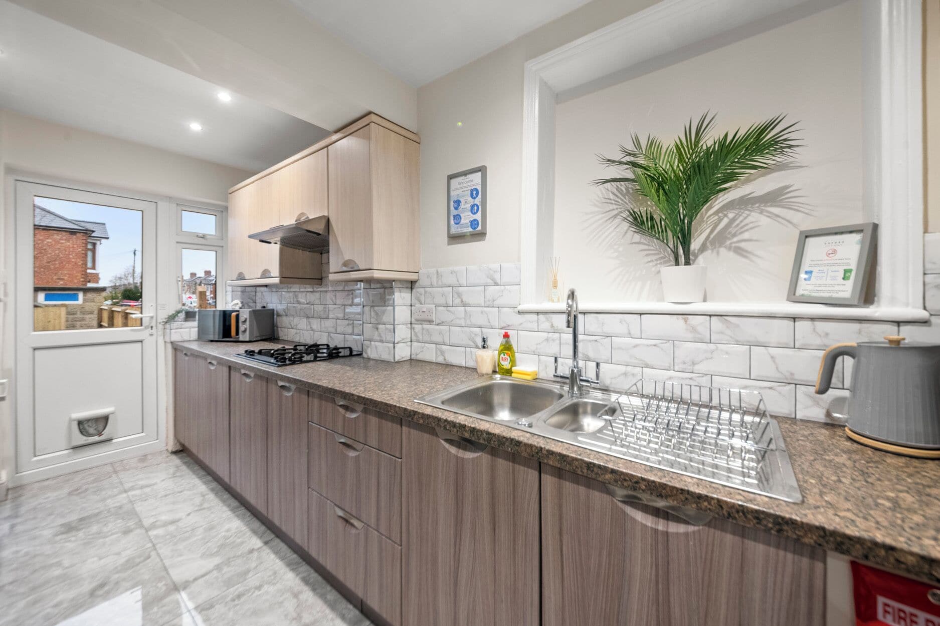 A modern kitchen with a built-in stove, stainless steel sink, and wooden cabinets.