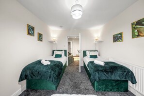 A room with two beds, a white ceiling light, and artwork on the walls. - Oxford City Stay Cooper House (Oxford)