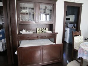 A wooden cabinet with glass doors, a table with a floral tablecloth, and a chair. - Charming 2-bedroom cottage steps to the Strand Hermosa Beach (Hermosa Beach)