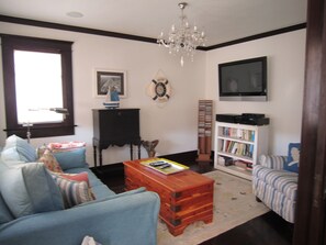 Una sala de estar con un sofá, una mesa de centro, una estantería, un televisor y una araña.