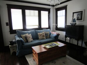 Un salon avec un canapé bleu, une table basse en bois, une lampe et un cadre photo accroché au mur.