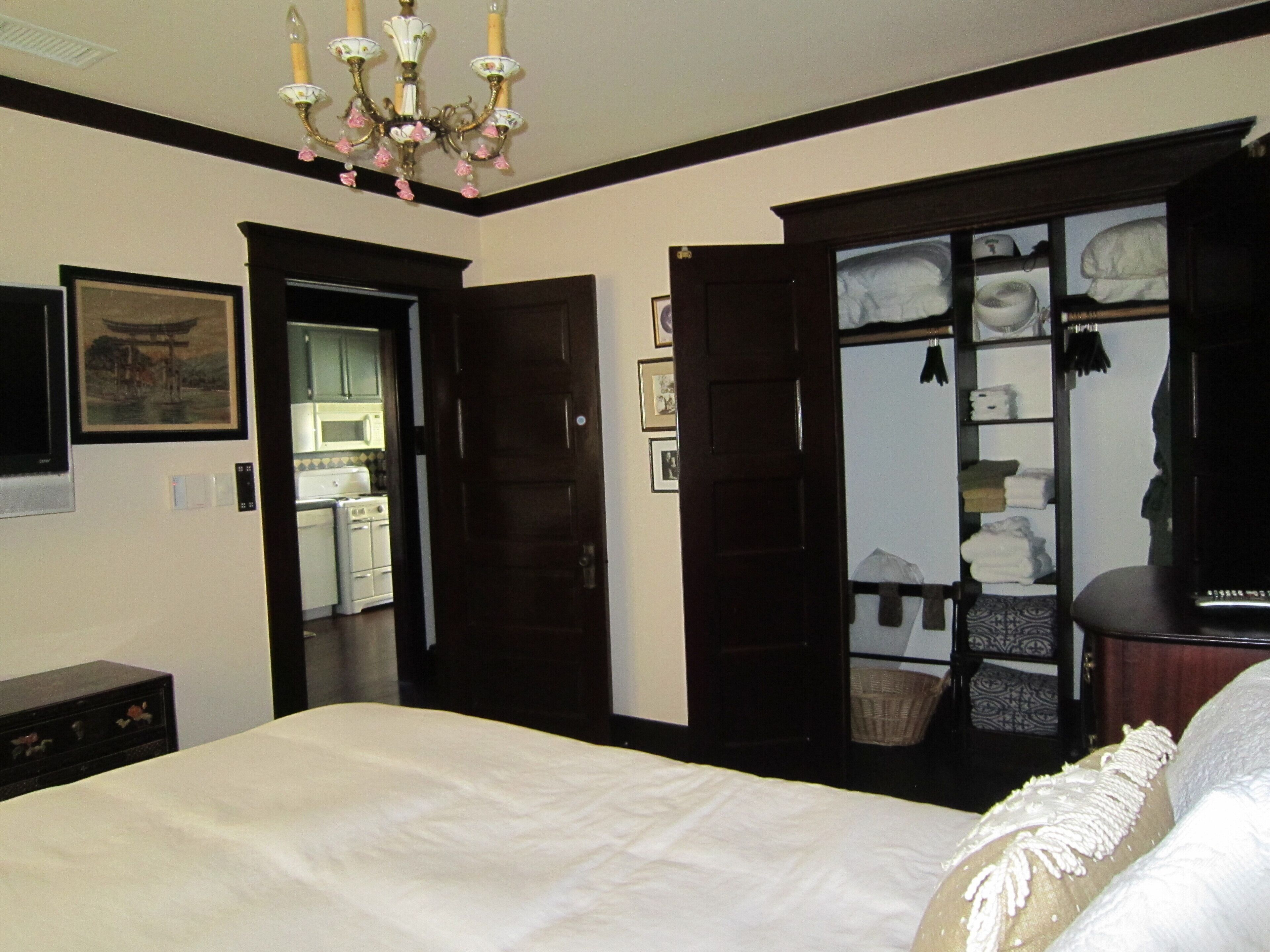 A hotel room with a bed, a wardrobe, a mirror, and a chandelier.