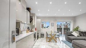 A modern kitchen with a dining area, a sofa, and a view of the outside. - Oxford City Stay Cowley House (Oxford)