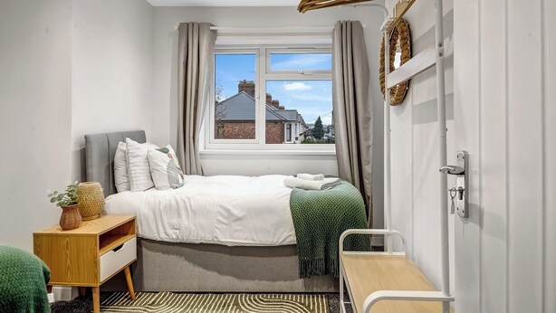 A bedroom with a bed, bedside table, and a window with curtains. - Oxford City Stay Cowley House (Oxford)