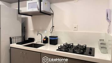 Una cocina moderna con estufa a gas, microondas y pileta.