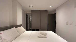 Habitació d'hotel amb un llit, un armari i una porta al bany.
