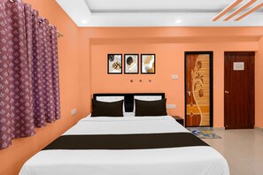 A hotel room with a bed, a door, and three framed pictures on the wall.