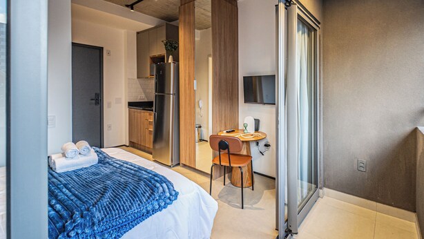 Una habitación de hotel moderna con una cama, un escritorio y vistas a través de un ventanal.