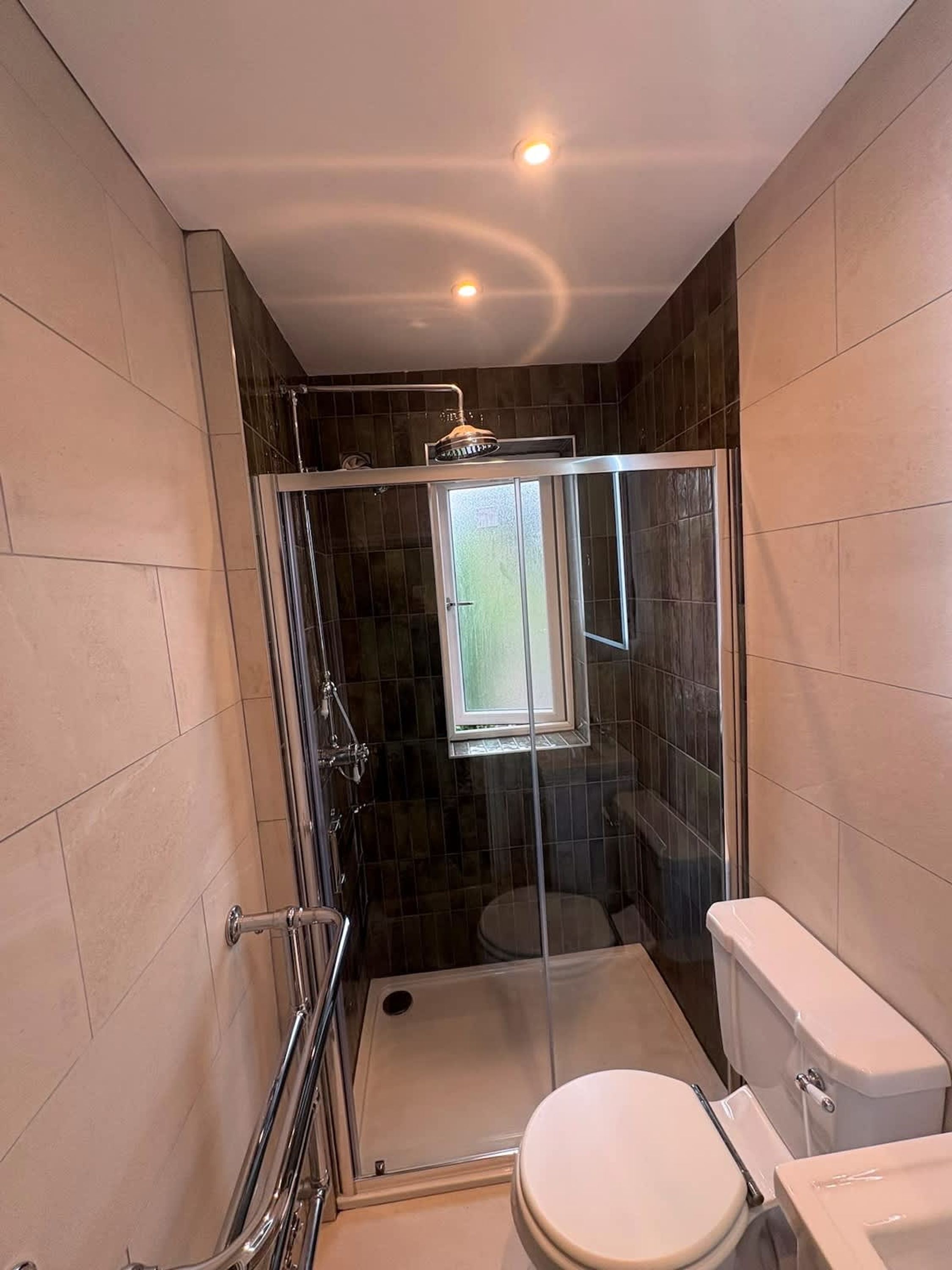 Un baño moderno con ducha envuelta en vidrio, un inodoro y una puerta de vidrio.