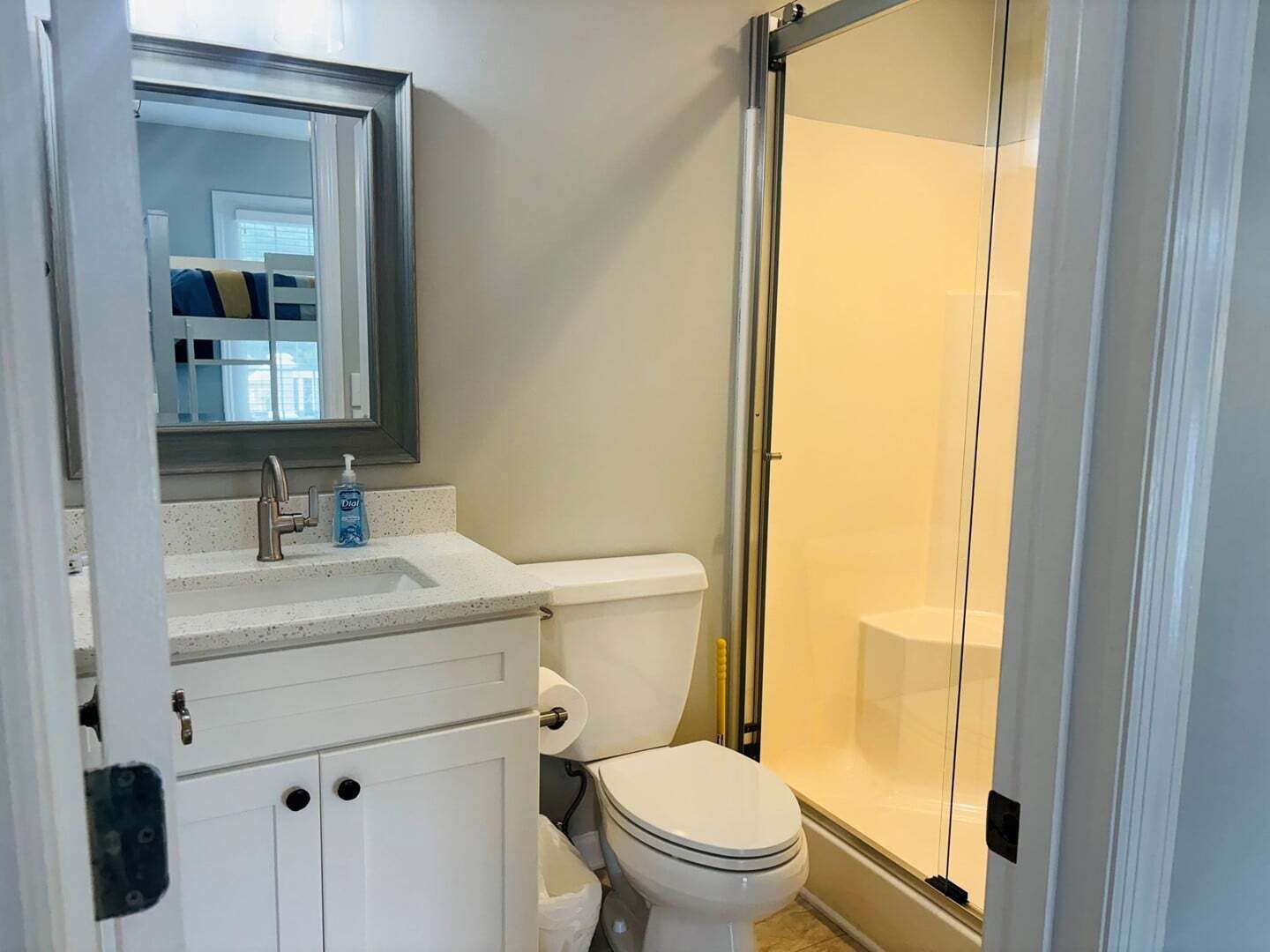 Een badkamer met toilet, wastafel, spiegel en douchecabine.