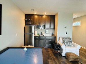 A compact living space with a kitchenette, a pool table, and a sofa. - 4BR second-row beach house with private pool, near Holden Beach. (Holden Beach)