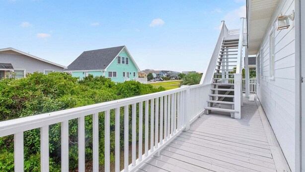 A wooden deck with a white railing, leading to a staircase with a white railing. - Sea Monkeys Beach Cottage: 3BR, 2BA  retreat in Holden Beach. (Holden Beach)