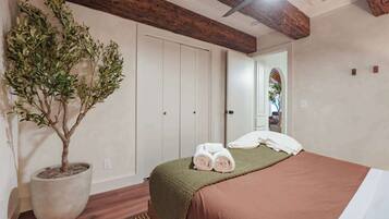 Un dormitorio con una cama, una planta en maceta y una puerta que da a otra habitación.