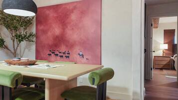 A dining area with a table, chairs, and a wall-mounted artwork depicting a herd of animals.