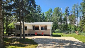 A single-story cabin with a gravel driveway, surrounded by trees. - Modern Rustic Cabin in Balaton Beach with Lake Access & Firepit (Balaton Beach)