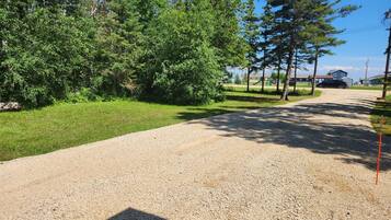 A gravel driveway leading to a residential area with houses and a playground.