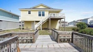 A two-story house with a front porch and a staircase leading to the upper level. - Canal-front 3BR, 2BA retreat with dock, WiFi, grill, and dog-friendly comfort. (Supply)