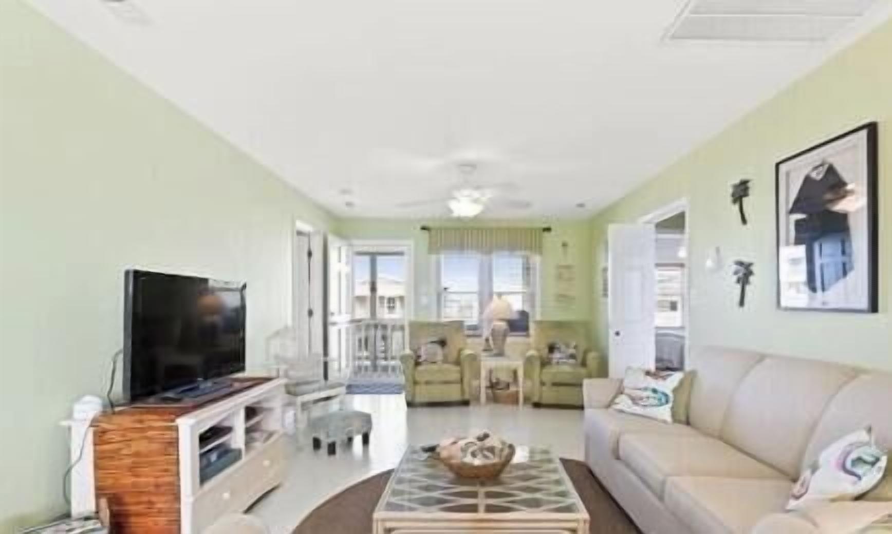 A living room with a flat-screen TV, a coffee table, a sofa, and a dining area with chairs.