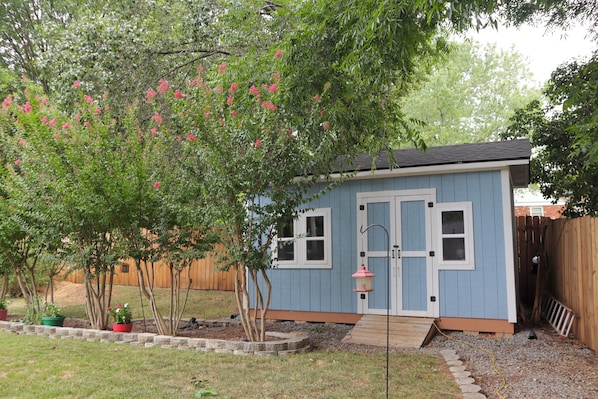 A small blue house with a wooden deck, a front door, and a window.