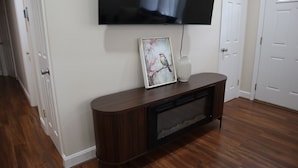 Een kamer met een wandgemonteerde flatscreen televisie, een lijst met een vogel erop en een vaas.