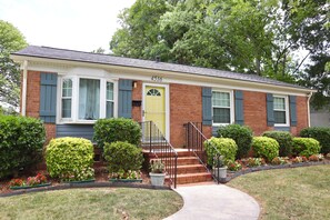 A two-story house with a front entrance, a yellow door, and a brick facade.