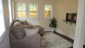 Een woonkamer met een modulaire bank, een potplant en een wandgemonteerde televisie.