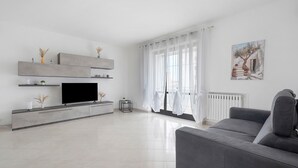 Una sala de estar moderna con televisor de pantalla plana, sofá gris y un cuadro en la pared.