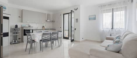 Cocina moderna con comedor, sofá y un amplio ventanal.