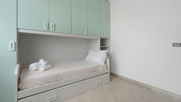 Habitación individual con armario empotrado, mesita de noche y toma de corriente en la pared.