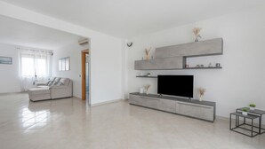 Una sala de estar moderna con un televisor de pantalla plana, un sofá y una mesa de centro.