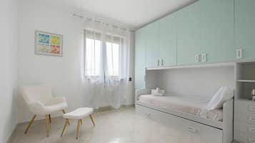 A bedroom with a bed, a chair, a cabinet, and a window with curtains.