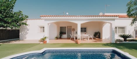 A residential property with a swimming pool, a patio with outdoor furniture, and a white exterior.