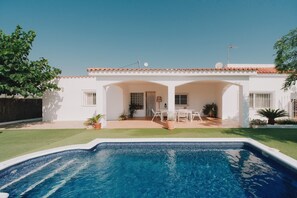 A residential property with a swimming pool, a patio with outdoor furniture, and a white exterior.