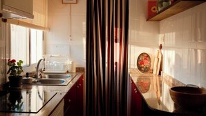 Una cocina con una isla central, horno empotrado y ventana con persianas.