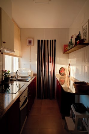 A kitchen with a central island, a built-in oven, and a window with blinds.