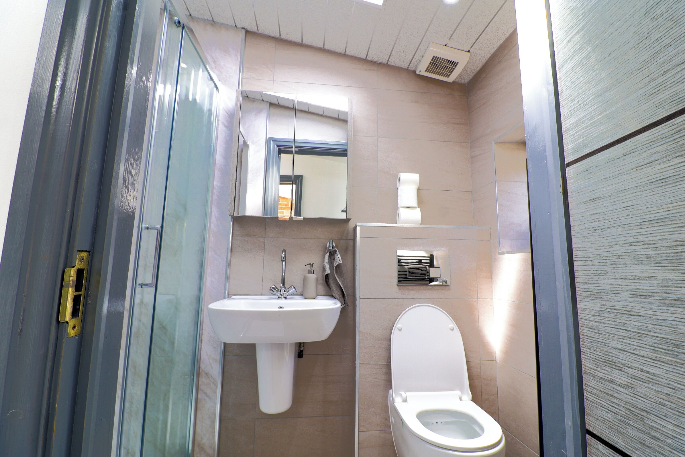 Ein kleines Badezimmer mit einem weißen Waschbecken, einer Toilette und einer Duschkabine aus Glas.