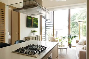 A modern kitchen with a gas stove, a glass enclosure, and a view of the outdoors. - Alluring New Apt w/ private Rooftop/Old city (Cartagena de Indias)
