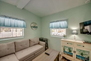 A living room with a sofa, a coffee table, a TV, and a cabinet with decorative panels. - 216 Pearl Cozy Pet Friendly Apartment near Beach (Fort Myers Beach)