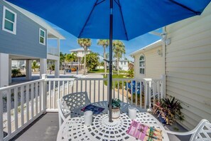 A covered outdoor seating area with a table and chairs, surrounded by a white railing, and overlooking a residential neighborhood. - 216 Pearl Cozy Pet Friendly Apartment near Beach (Fort Myers Beach)
