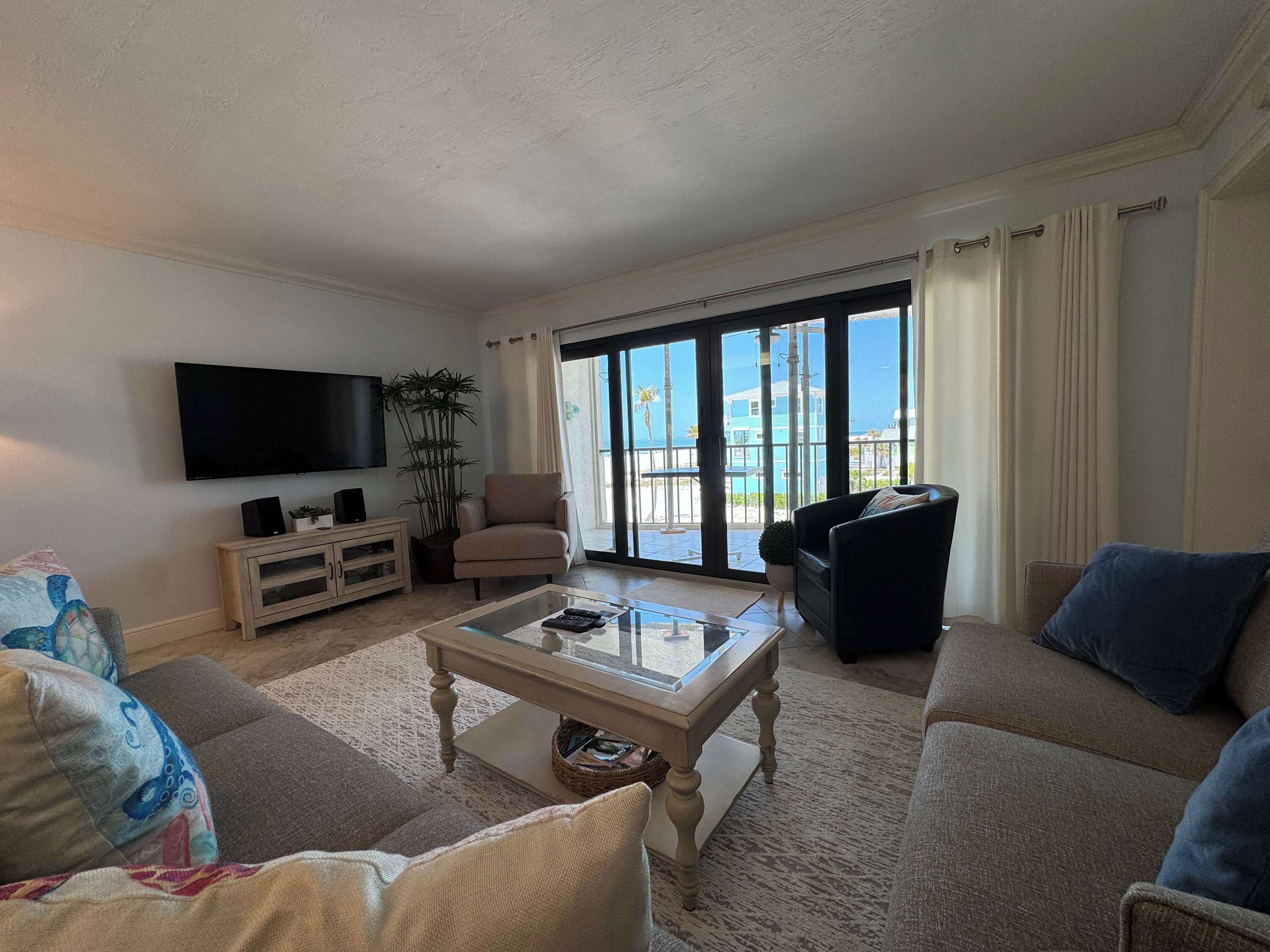 A living room with a flat-screen TV, a sofa, a chair, and a coffee table.