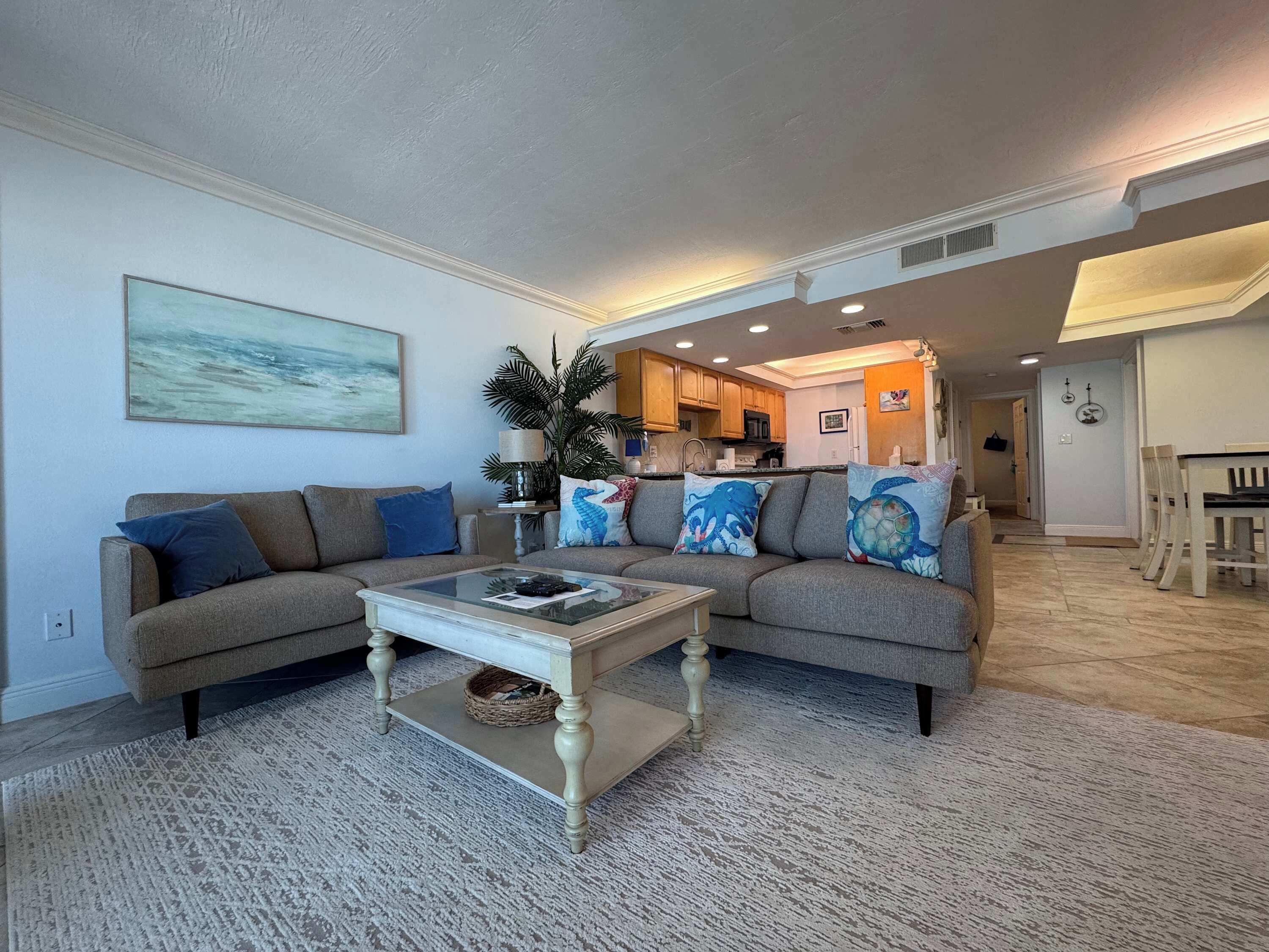 A living room with a sectional sofa, a coffee table, and a painting on the wall.